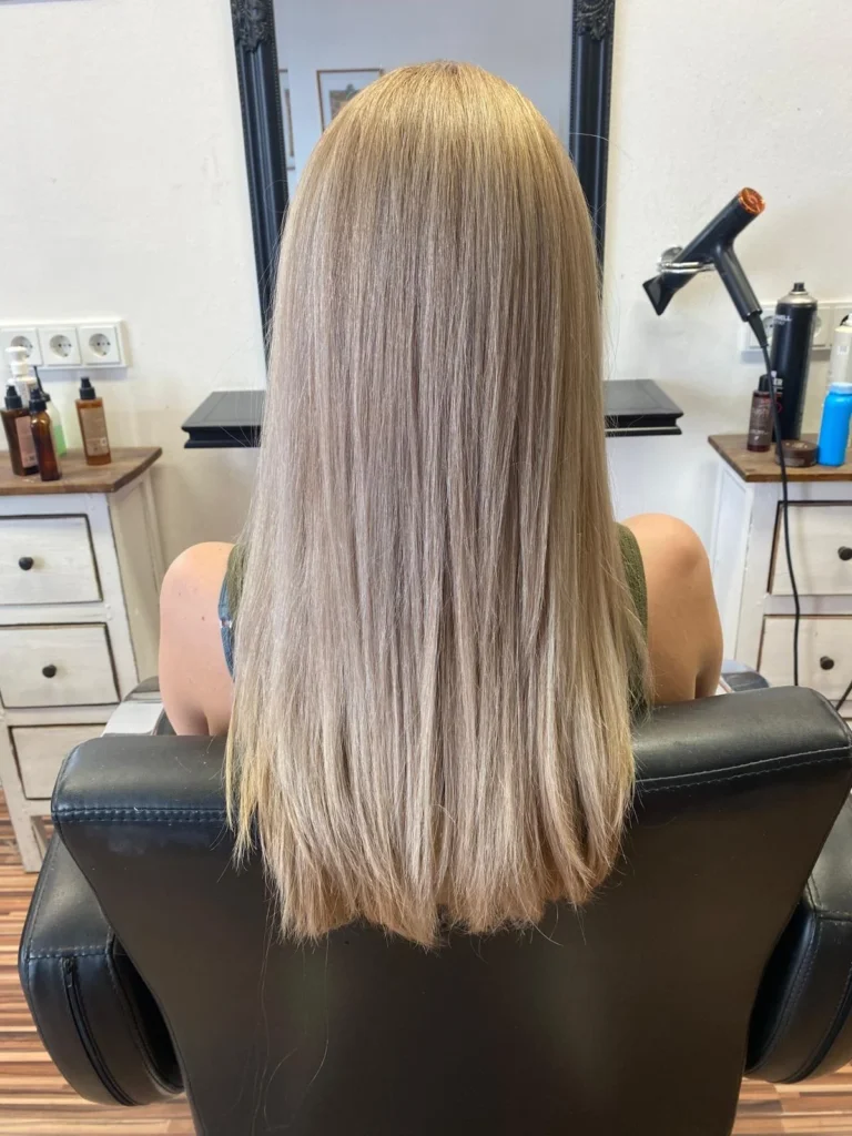 Lange glatte aschblonde Haare im Friseurstuhl