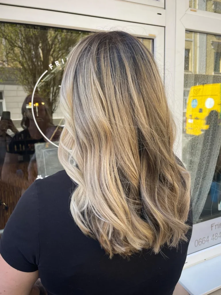 Lange blonde Balayage-Wellen bei Friseur ist Kopfsache